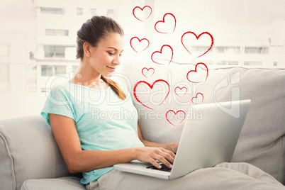 Composite image of happy woman sitting on couch using her laptop