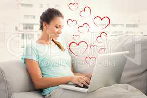 Composite image of happy woman sitting on couch using her laptop