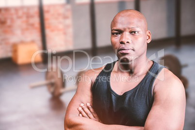 Composite image of portrait of bald bodybuilder with arms crosse