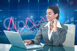 Composite image of smiling businesswoman using laptop at desk