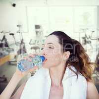 Composite image of beautiful brunette drinking water