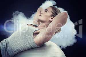 Composite image of muscular woman doing sit ups on exercise ball