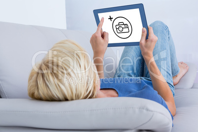 Composite image of blonde woman using her tablet on the couch