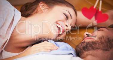 Composite image of smiling couple lying on the floor