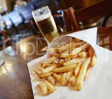 Potatoes fries in a little white paper bag on wood table in brus