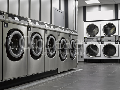 A row of industrial washing machines in a public laundromat