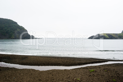 Wet beach in small bay between coastline