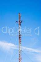 Tall red and white antenna on blue sky