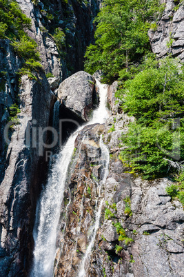 Mountain waterfall flowing down rocky cliff