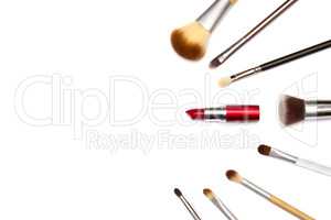 Assorted make up brushes and red lipstick on white background