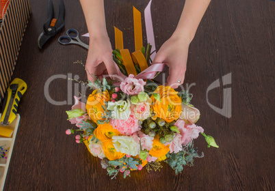 Florist making bright orange and pink bouquet