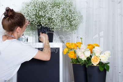 Florist writing on black graphit desk, yellow and white flowers