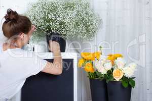 Florist writing on black graphit desk, yellow and white flowers