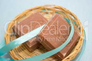 brown soap with a blue ribbon in a basket on a blue background