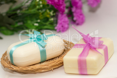 Two pieces of soap with a basket with a bow and flowers