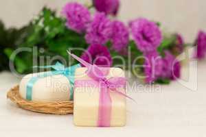Two pieces of soap with a basket with a bow and flowers
