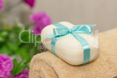 Soap with blue ribbin bow on towel and witn purple flowers on th