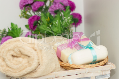 Two pieces of soap with a basket with a bows , flowers and towel