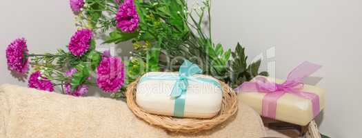 Two pieces of soap with a basket with a bows , flowers and towel