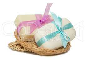 isolation photo of two bars of soap with a ribbon in a basket on