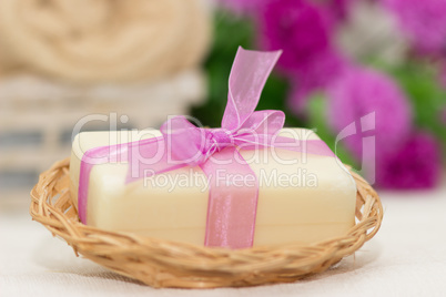 Big piece of beige soap in busket, witn purple bow, flowers on b