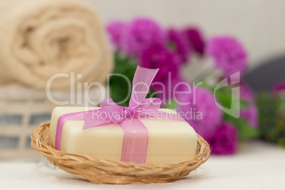 Big piece of beige soap in busket, witn purple bow, flowers on b