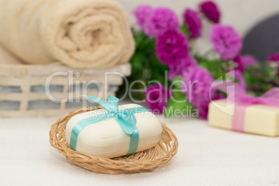 Big piece of beige soap in busket, witn blue  bow, flowers and t