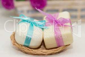 Two pieces of soap with a basket with  bows
