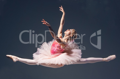 Beautiful female ballet dancer jumping on a gray background