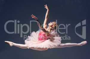 Beautiful female ballet dancer jumping on a gray background