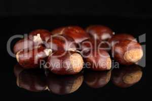 Chestnuts on a black reflective background