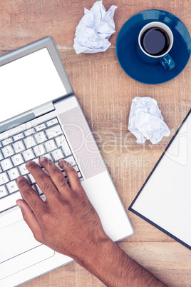 Stressed businessman using laptop by coffee at desk