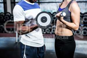 mid section of fit couple lifting dumbbells