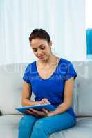 Smiling woman using tablet on sofa