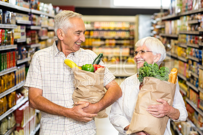 Smiling senior couple holding grocery bags