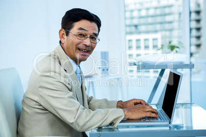 Smiling asian businessman working on laptop