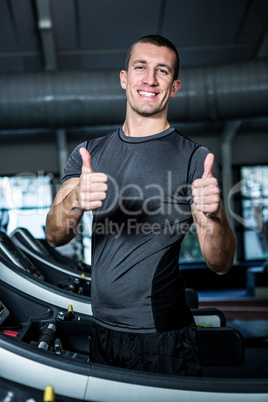 Muscular man on treadmill showing thumbs up Muscular man on treadmill showing thumbs up