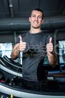 Muscular man on treadmill showing thumbs up