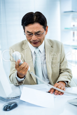 Frustrated businessman looks his phone