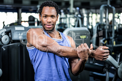 Smiling muscular man stretching arms