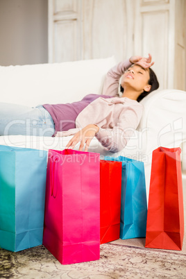 Shopping bags against brunette lying on sofa