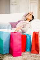 Shopping bags against brunette lying on sofa