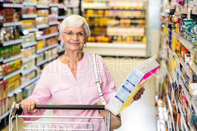 Smiling senior woman holding corn flakes box