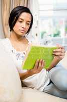 Focused brunette reading a book on the sofa