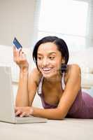 Smiling brunette using laptop and holding credit card