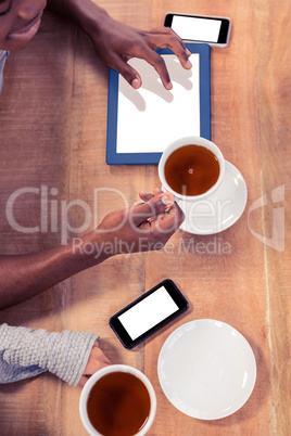 Colleagues holding coffee cups while using technologies