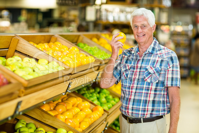 Smiling senior man holding orange