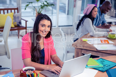 Beautiful businesswoman using laptop while working with colleagu Beautiful businesswoman using laptop while working with colleagu