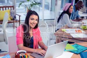 Beautiful businesswoman using laptop while working with colleagu