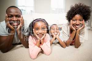 Happy family lying on the floor looking at the camera